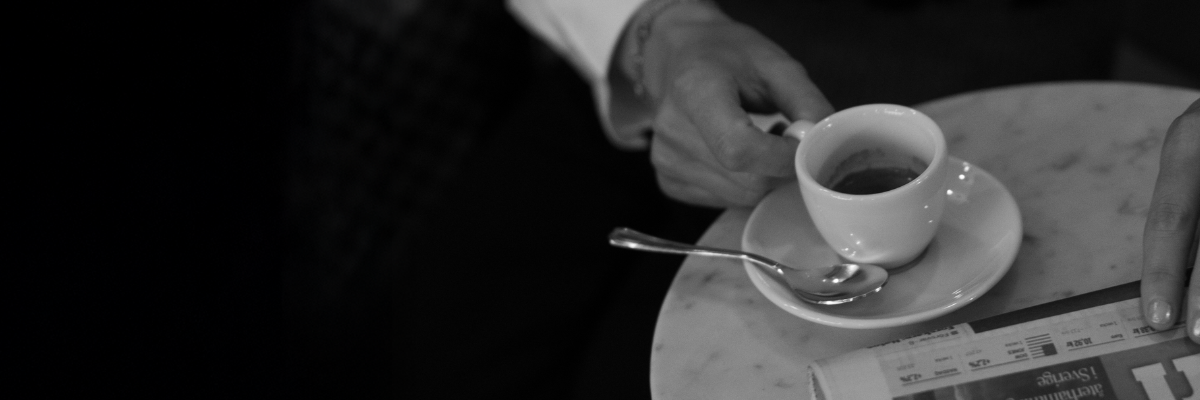 En person som håller en kaffekopp och läser en tidning